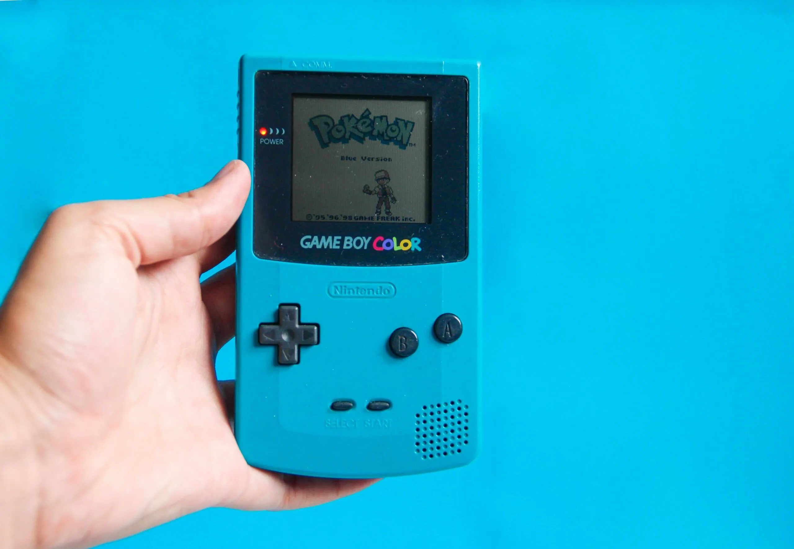 Hình ảnh máy Game Boy cổ điển đang chạy game Pokémon Blue, gợi nhớ về thời kỳ hoàng kim của game cầm tay và tạp chí game.