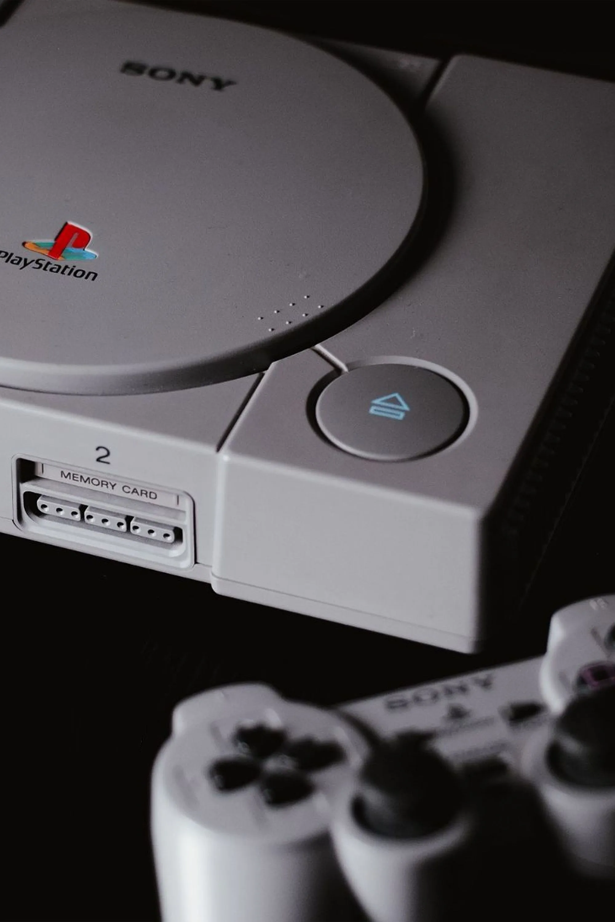 Hình ảnh chiếc máy PlayStation 1 cổ điển màu xám cùng bộ tay cầm đặc trưng, biểu tượng của kỷ nguyên game console đầu tiên của Sony.